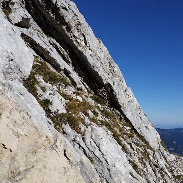 Imposante Felswand mit steiler Flanke und Blick in ein Tal