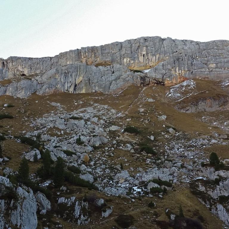 Ein großes Bergmassiv mit sichtbarer Schichtung und steilen Abhängen unter einem hellen Himmel.