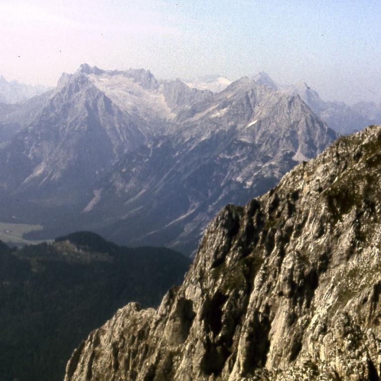 Panoramablick von einem Berghang auf eine weitläufige Gebirgskette