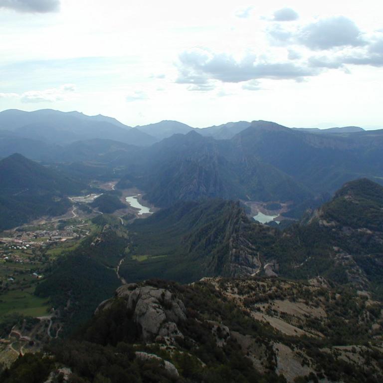 Panoramaaufnahme einer weiten, bergigen Landschaft mit einem Fluss, der ein tiefes Tal durchquert.