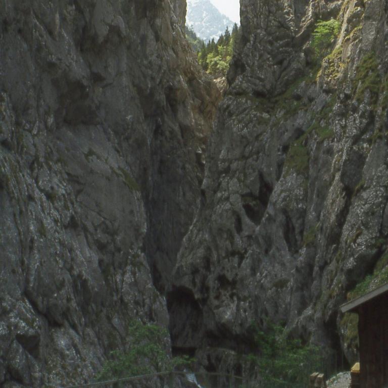 Ein tief eingeschnittener Canyon mit steilen Felswänden und einem Wanderweg am Grund.