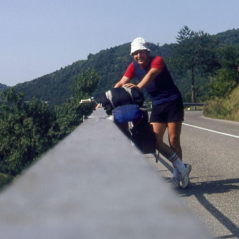 Eine Sportlerin bewegt sich auf einer Landstraße mit einer Kulisse aus grünen Hügeln.