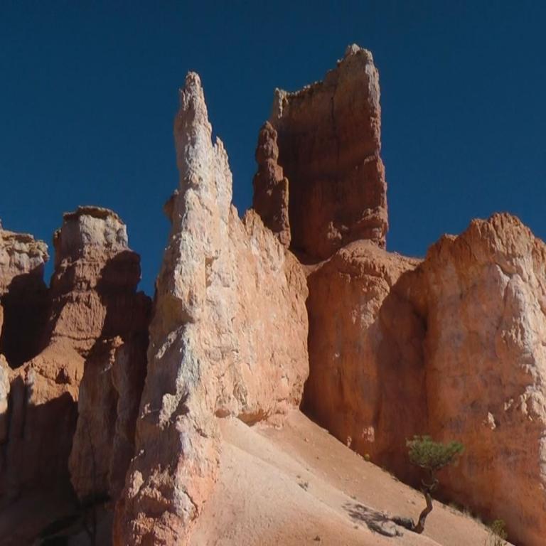 Monumentale, ockerfarbene Sandstein-Klippen, die dramatisch gegen einen tiefblauen Himmel emporsteigen.