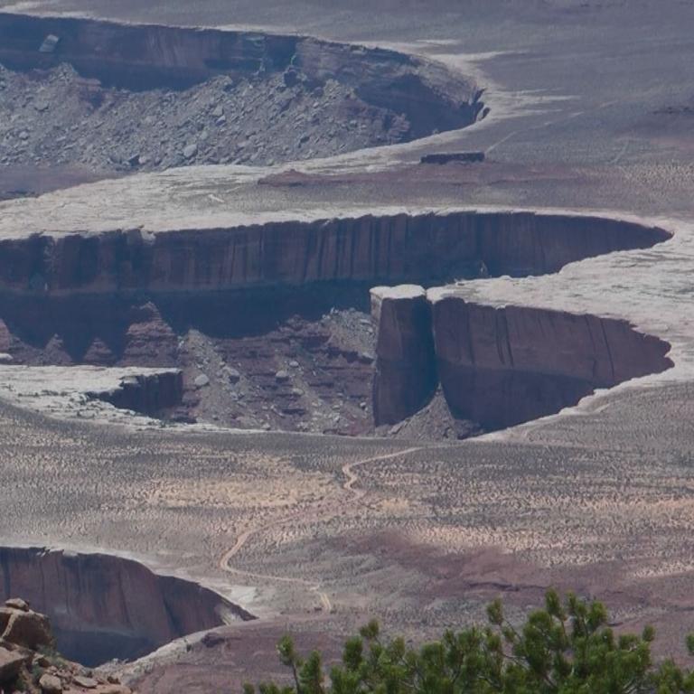 Panoramablick auf eine ausgedehnte Canyonlandschaft mit tief eingeschnittenen Klippen und einem mäandrierenden Flusstal.