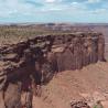 Eine weite Aufnahme des Canyonrandes mit steilen Felswänden und einer kargen Wüstenlandschaft.